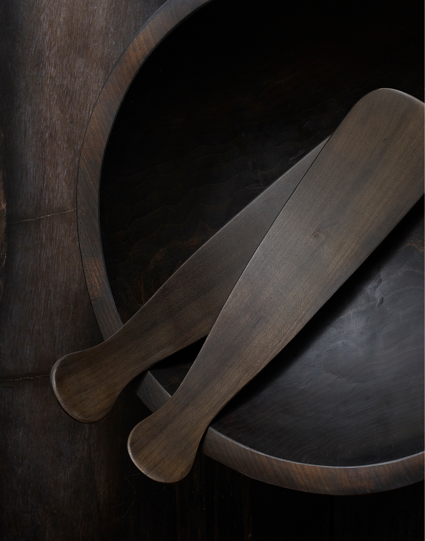 Ebonized cherry wood salad servers on a dark wood bowl
