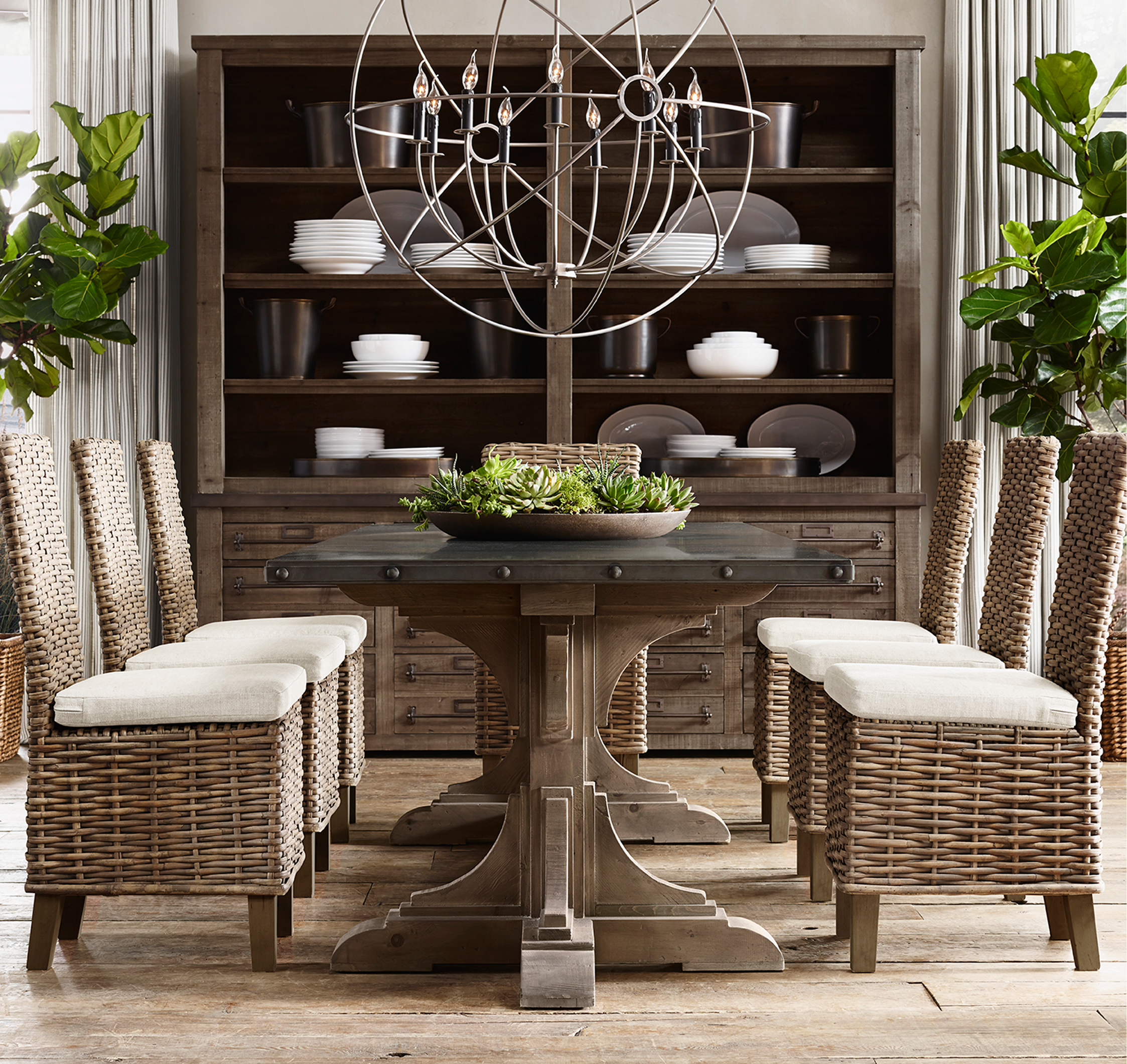 Rectangular dining room, wicker chairs, orb chandelier, hutch with succulents