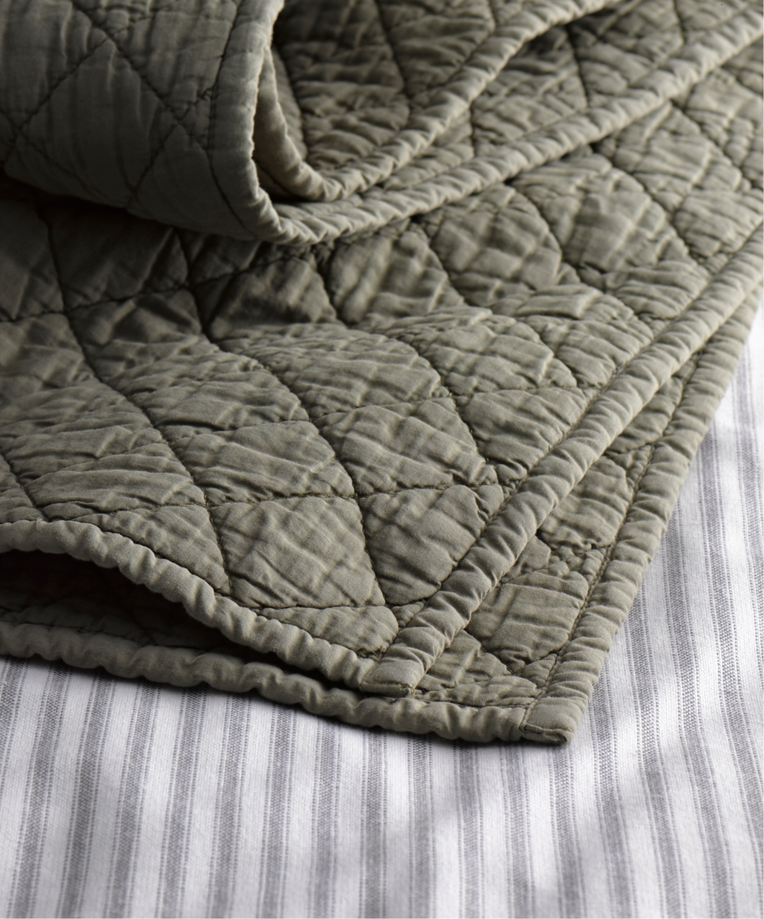 Sage-green Henley-stripe duvet folded on a striped sheet