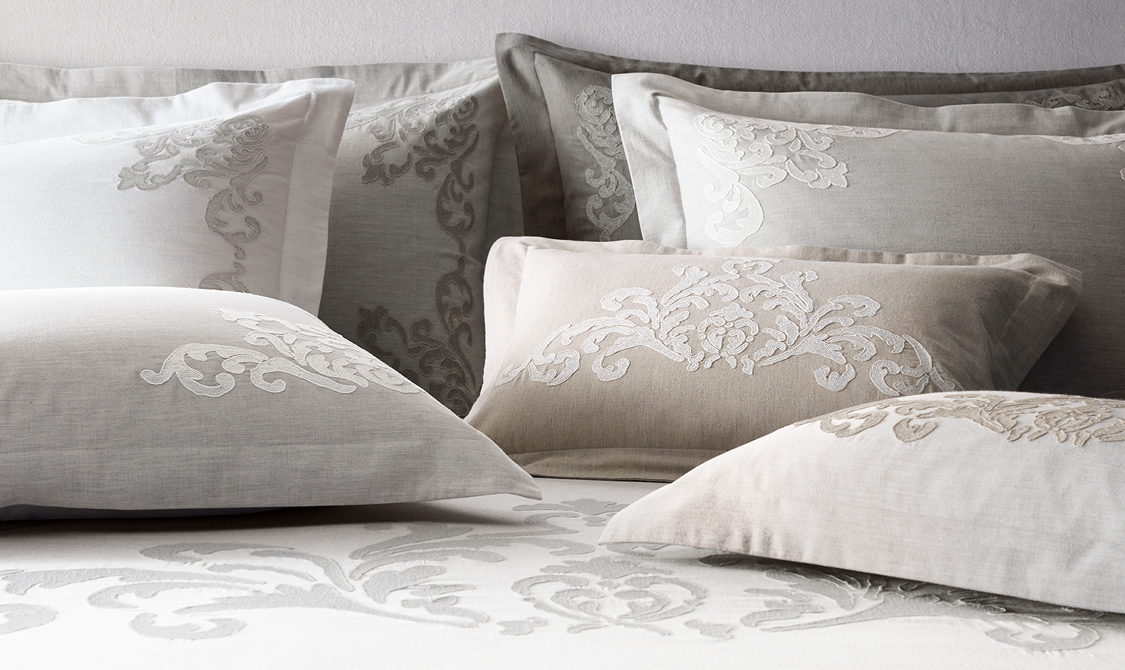 Embroidered vine bedding collection, layered gray, white, and tan shams