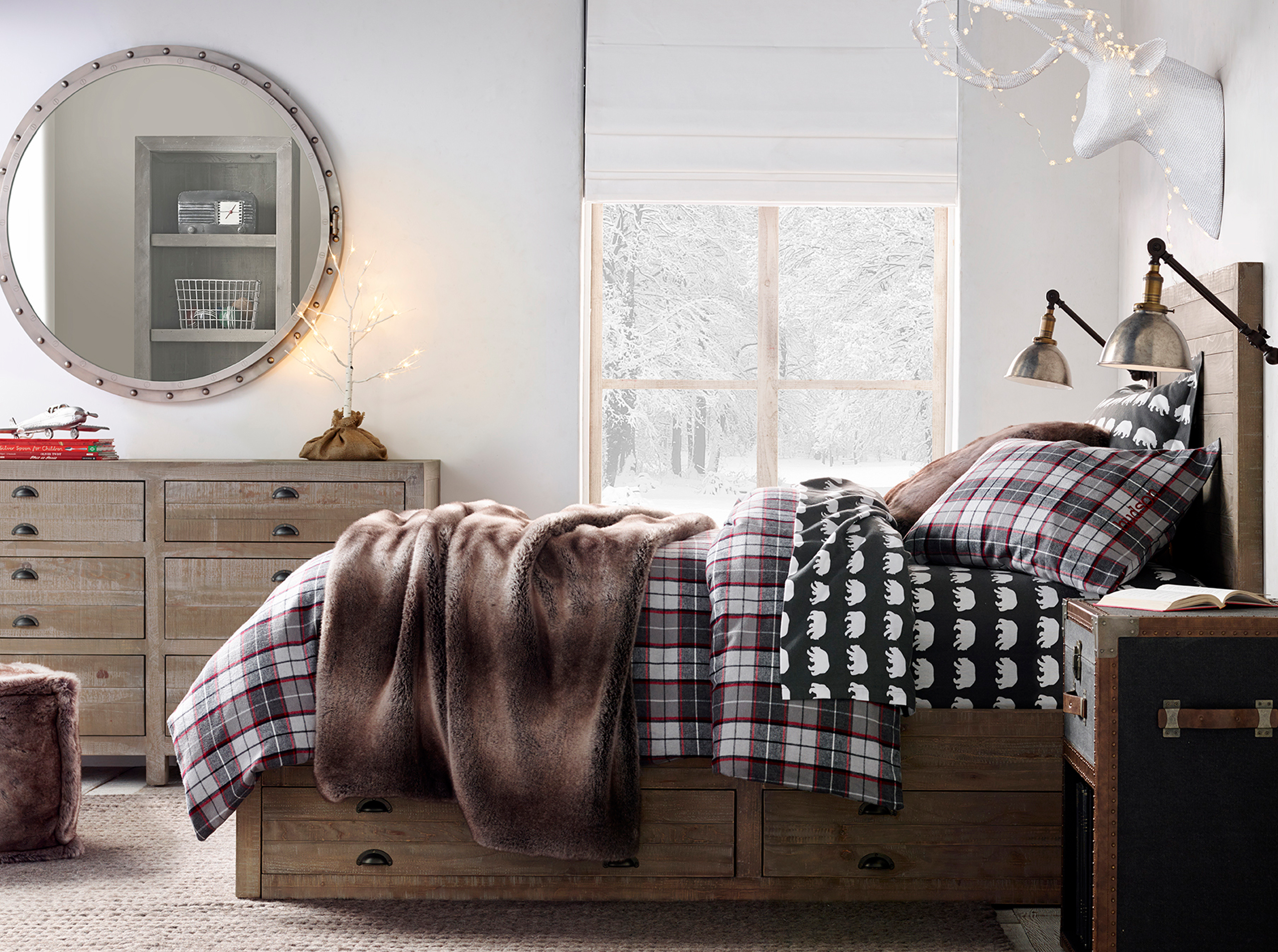 Boy's winter bedroom, round mirror, plaid bedding, lit deer head, snowy window