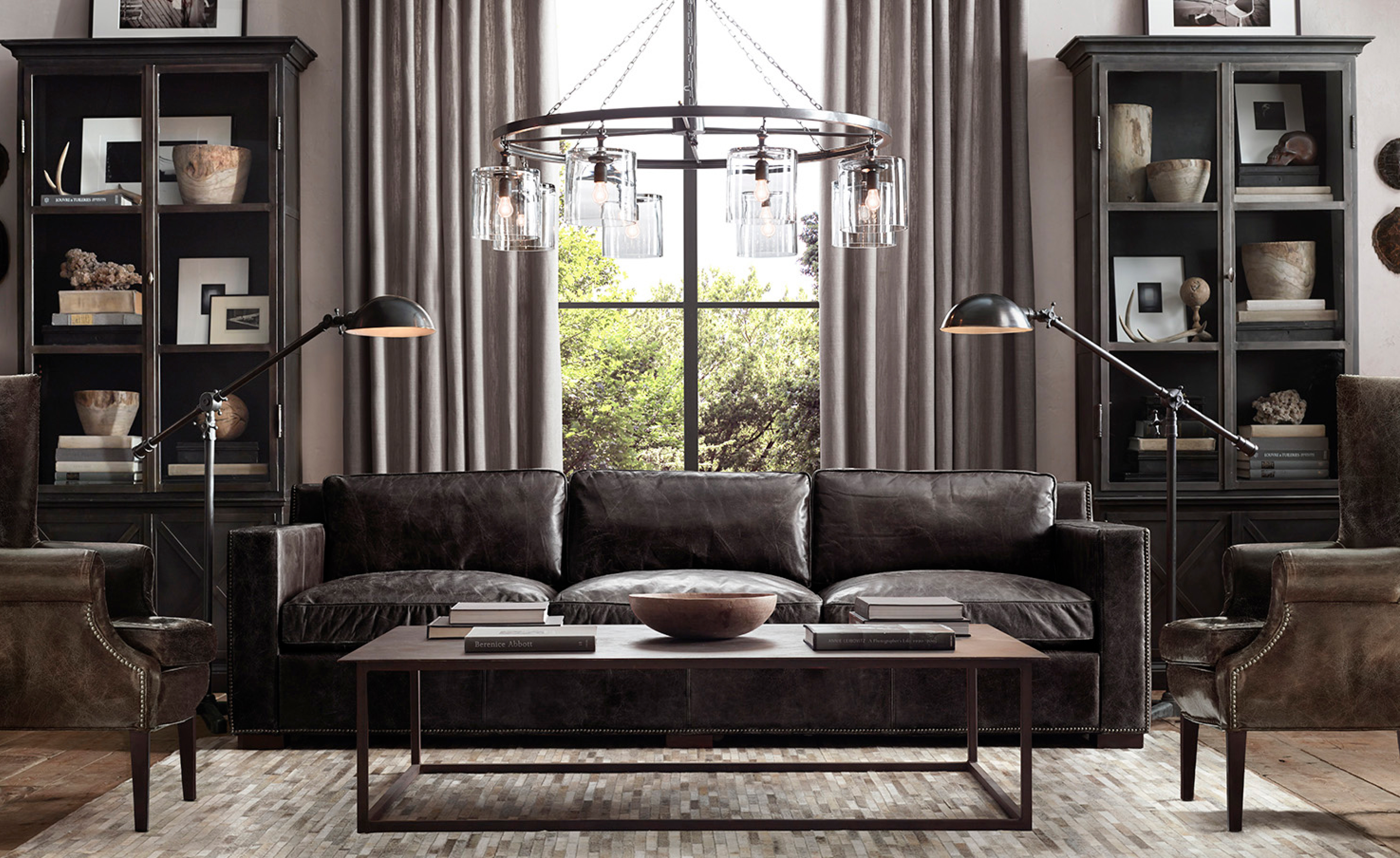 Dark leather chesterfield sofa, wingback chairs, glass-front cabinets